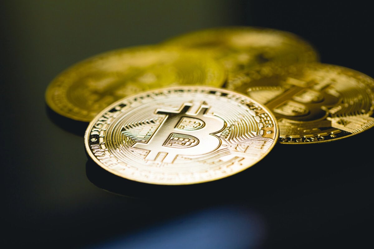 Gold Bitcoin on the surface of a dark table with glass in close-up photography.