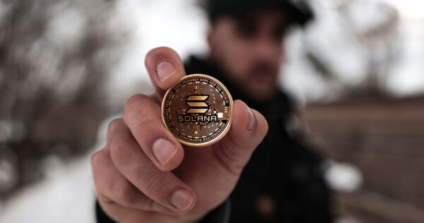Man holding Solana cryptocurrency coin